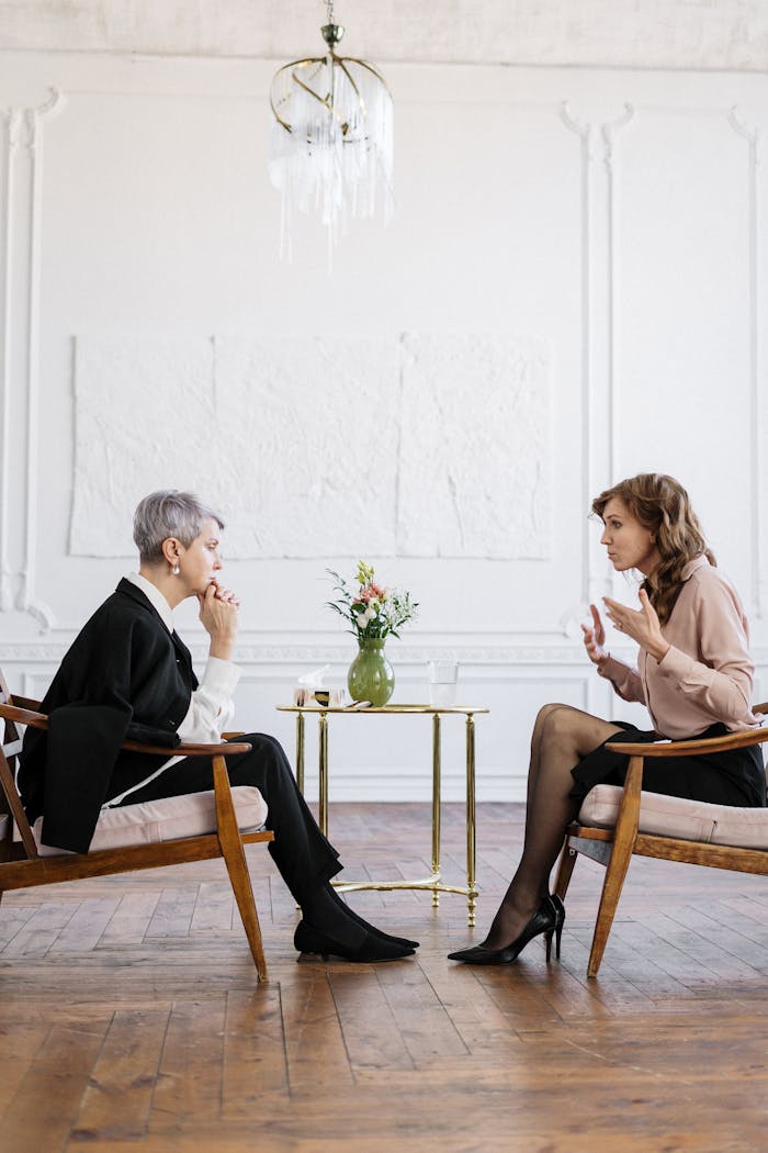 services-04 Two women engaged in a counseling session in a bright, modern loft setting.